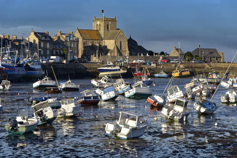 port at low tide at the end of the sunny day and church of saint-nicolas of barfleur, a commune in the peninsula of cotentin in the manche departmentin lower normandy in north-western france