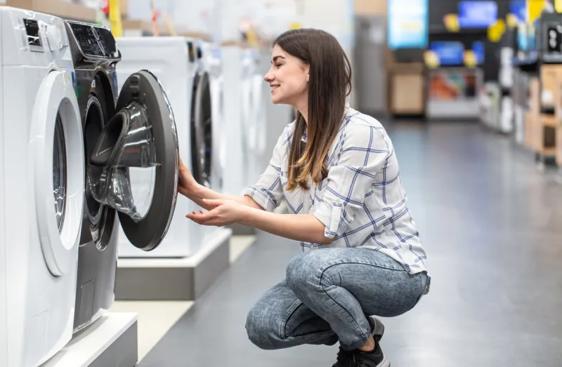 a young woman in a store chooses a washing machine the concept of shopping