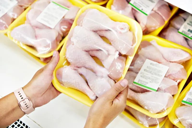 human hands with chicken meat in the store