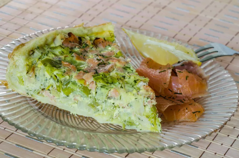 portion of salmon and leek quiche with smoked salmon and lemon