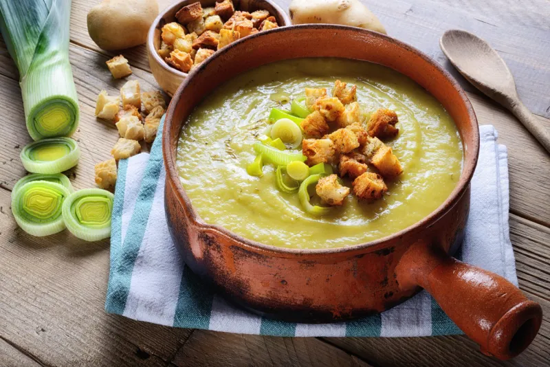 leek and potato soup with croutons on rustic wooden table, close-up