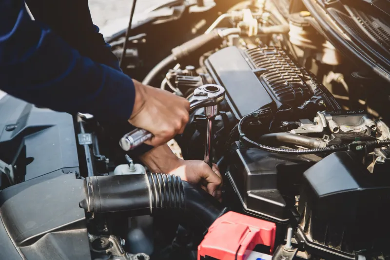 auto mechanic hands using wrench to repair a car engine concepts of car insurance support and services