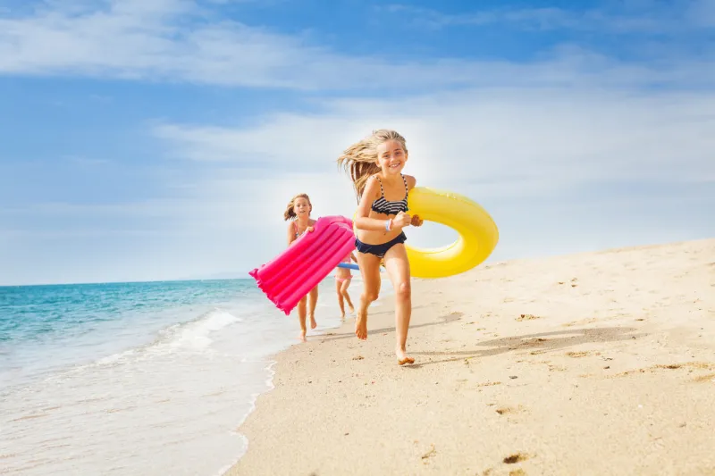 happy kids running with swimming tools on sandy beach in summer