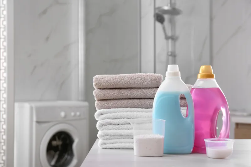 stack of folded towels and detergents on white table in bathroom