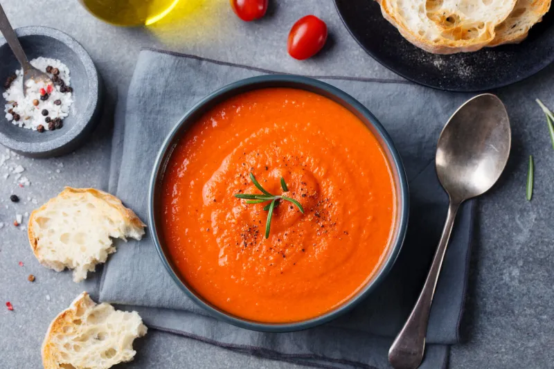 tomato soup in a black bowl on grey stone background top view copy space
