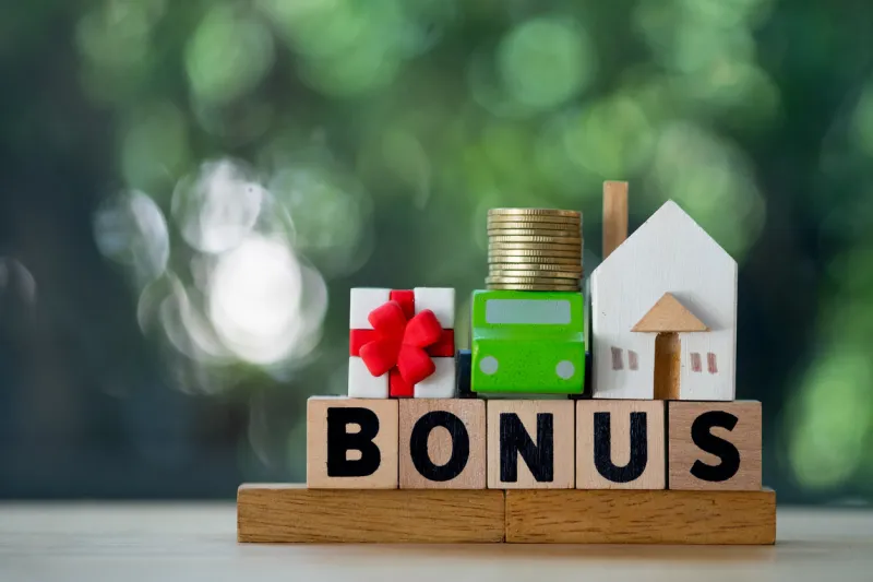 miniature home, car and money put on wood block in word bonus yearly bonus concept bonus is motivation in work