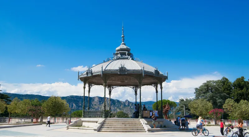peynet kiosk in valence with hills at the background, small group of people walking, cycling around
