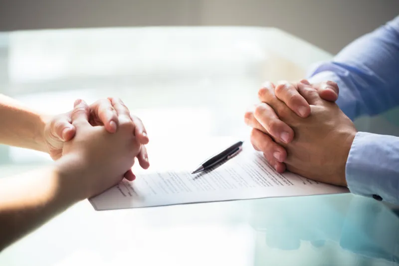 close-up of two businesspeople hand with document on desk