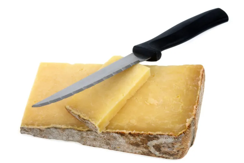 pieces of laguiole cheese with a knife in close-up on a white background