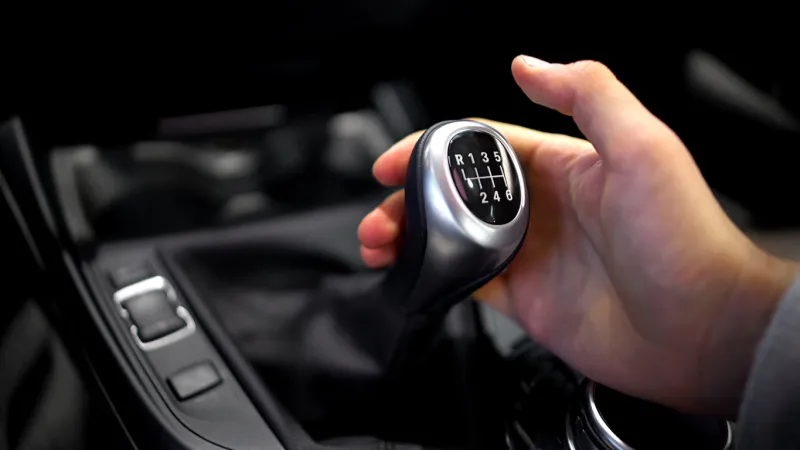 male hand holding manual gearbox in car, test drive of new automobile, closeup