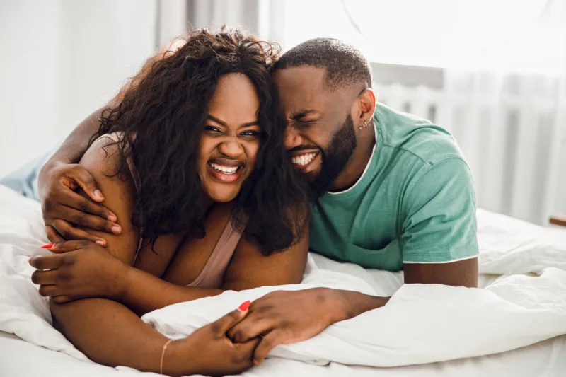 gladsome afro american couple lying on the bed and holding hands