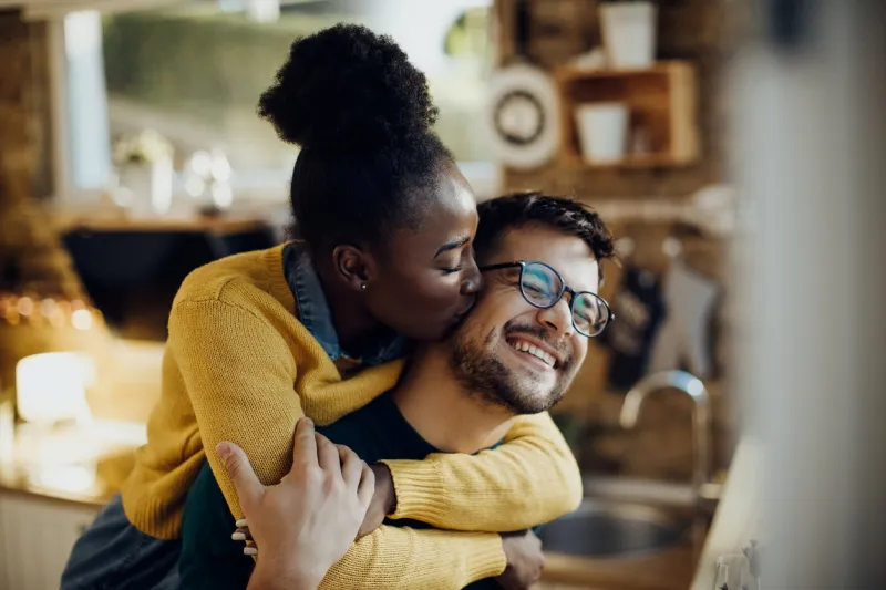 young african american woman kissing her boyfriend having fun with him at home