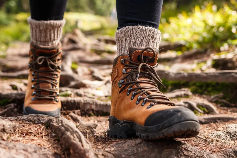 hiking boot legs on mountain trail during trekking in forest leather ankle shoes