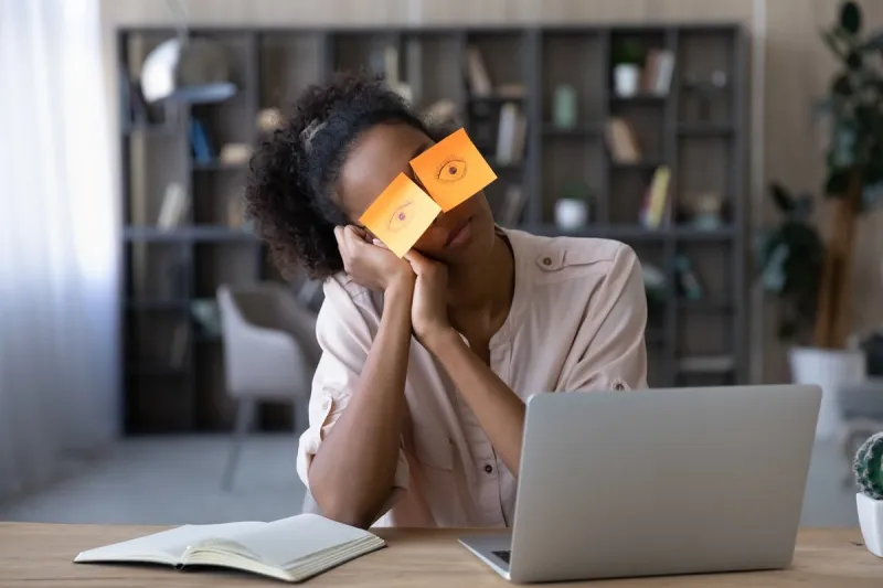 exhausted young african american woman work on computer at home office, have sticker pads on eyes feel sleepy tired millennial biracial female employee student suffer from exhaustion or fatigue