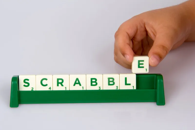 konak,İzmir,turkey- june 15, 2014  a kid's hand putting scrabble letter tile on the board and scrabble distributed by mattel