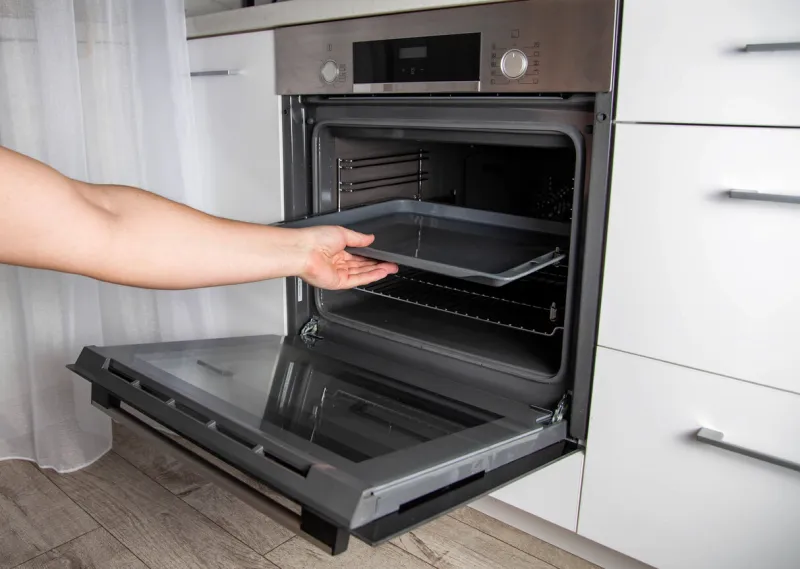 modern electric oven with telescopic rails and steel baking tray hinged oven door black oven in a white kitchen automatic cooking program, distribution