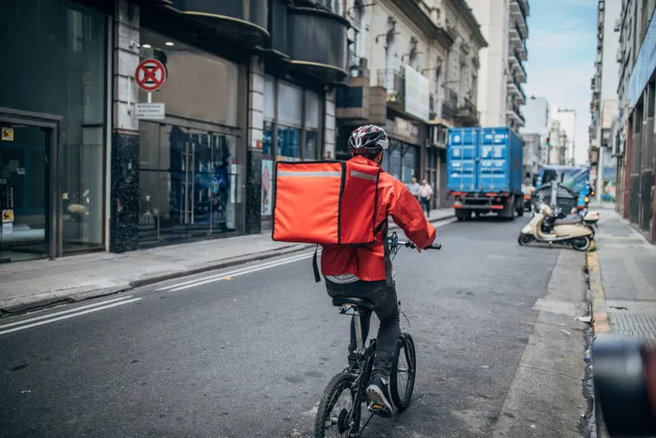 one man, delivery boy on bicycle, delivering pizza in city