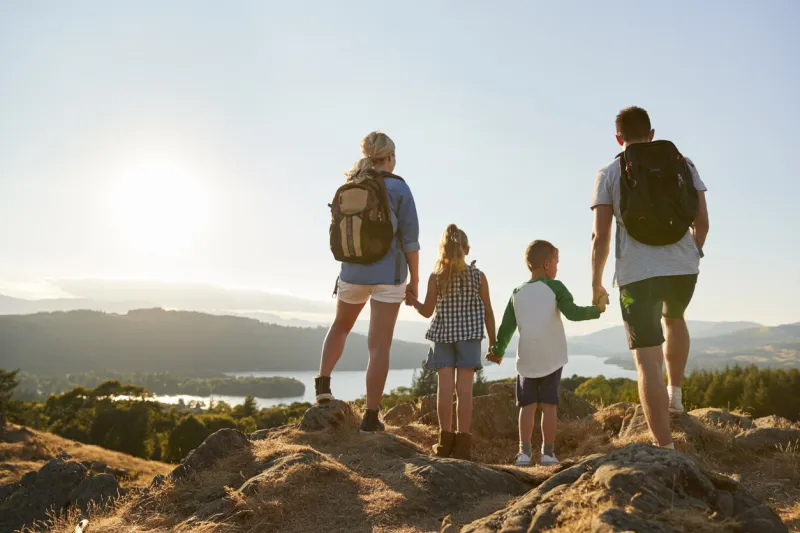 rear view of family standing at top of hill on hike through countryside in lake district uk