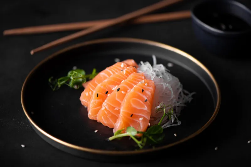 slices of fresh salmon with radish and soy sauce on plate