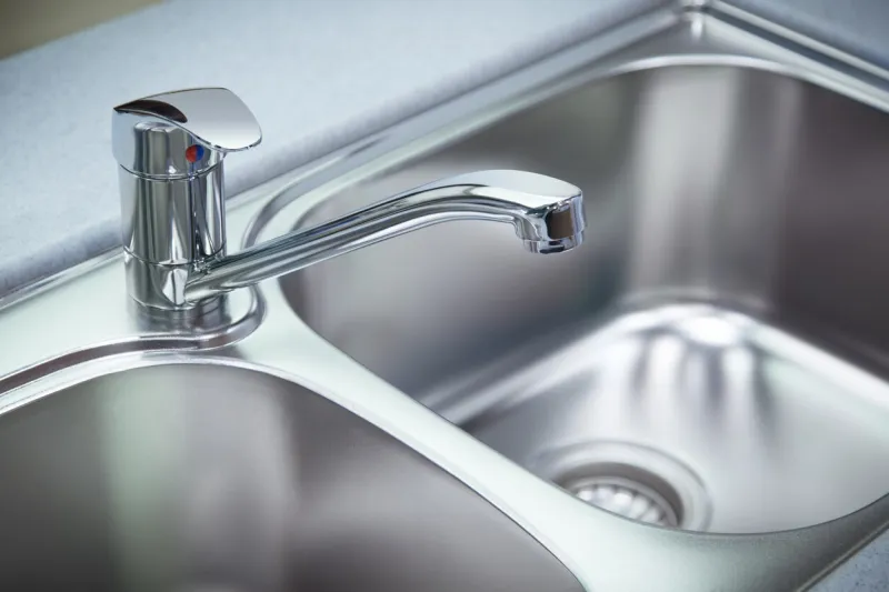 close up shot for the clean chrome tap and washbasin in a kitchen