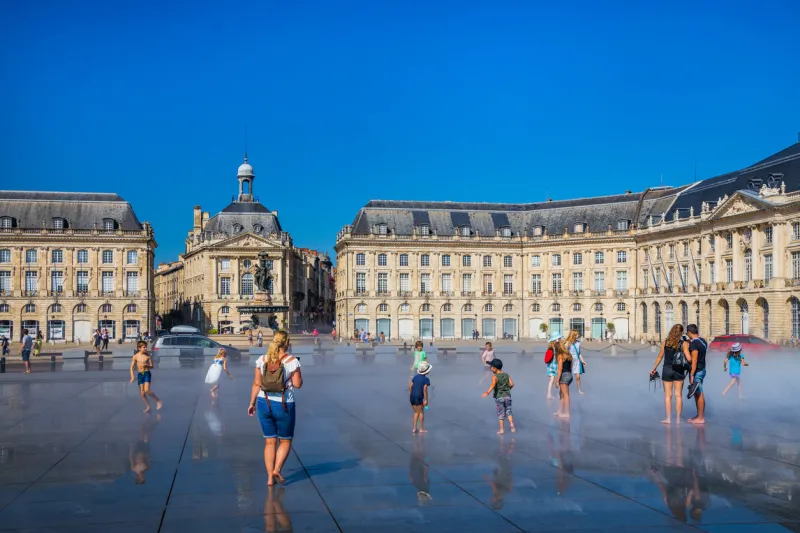tourists and kids having fun on the mirroir d'eau (water mirror) of the place de la bourse in bordeaux france on a hot summer day during a heat wave