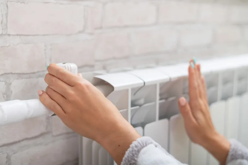 close-up of a female hand regulating the temperature of a heating radiator