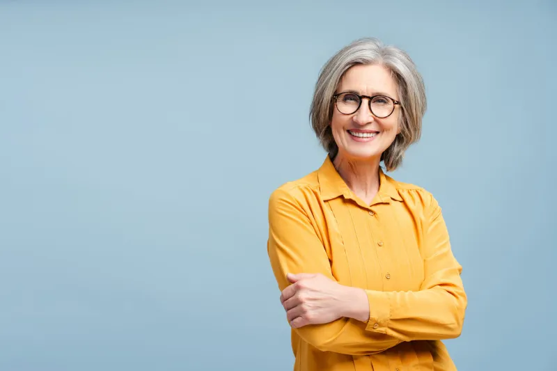 attractive smiling business woman, manager, financier wearing eyeglasses looking away isolated on blue background portrait of confident gray haired ceo holding arms crossed successful business