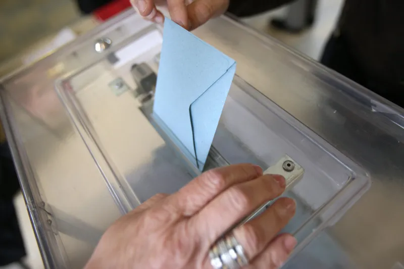 france 05 06 2012 this colorful image depicts a man placing an election envelope in a plastic ballot box at a polling station