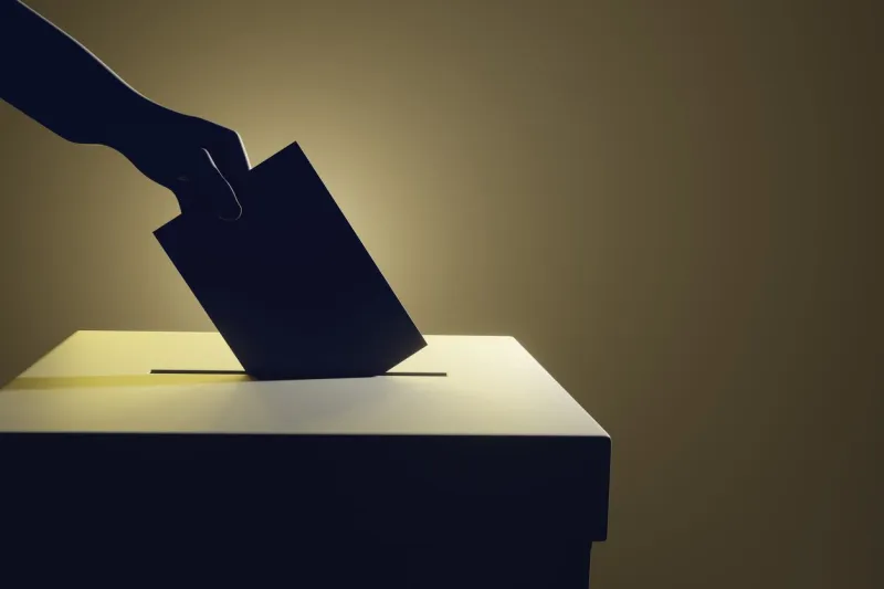 silhouette of a hand putting a vote into the voting box on pale yellow background illustration of the concept of legislative election
