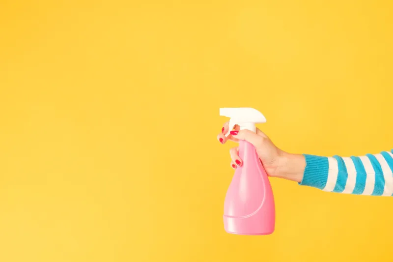 home cleaning chores woman hand armed with atomizer copy space on yellow background