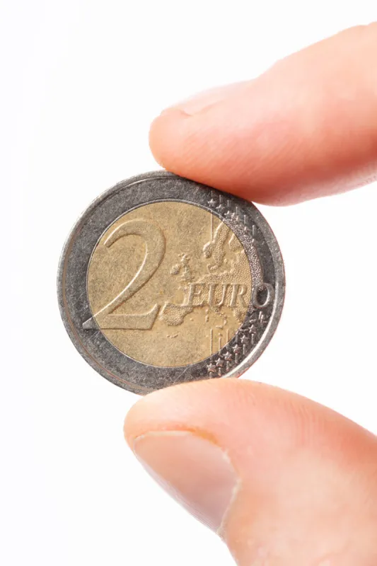 close-up of caucasian male fingers holding a two euro coin u20ac2 on a white background