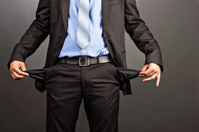 business man showing his empty pockets on gray background