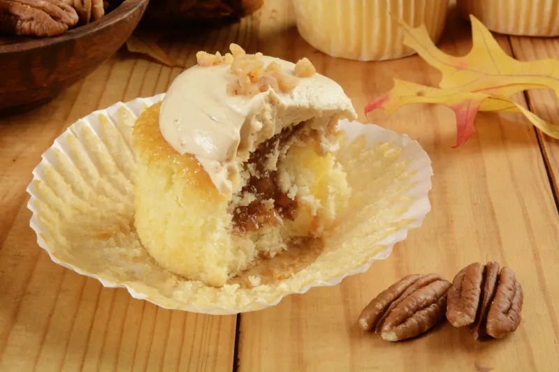 un cupcake aux pommes au caramel avec des noix de pécan sur une table en bois rustique