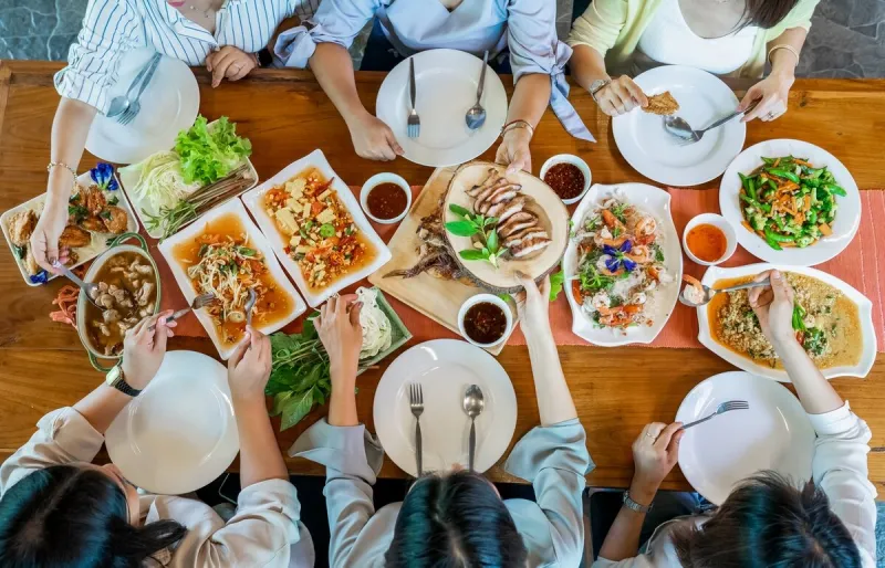 topview of thai local food such as somtum papaya spicy salad, grilled pork, tomyum, vegetable and shrimp curry are arranged on wood table