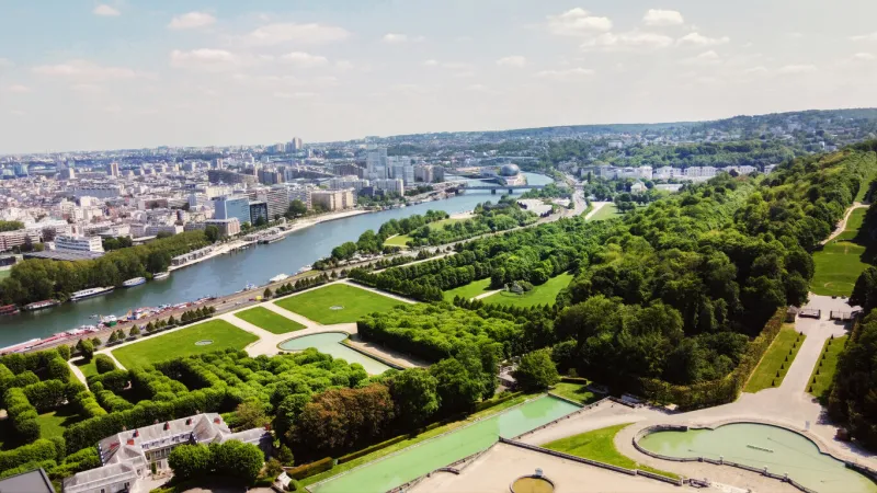 drone point of view on seine river and park of national estate de saint-cloud and le seine musicale (egg-shaped structure for music and dance) green color water in ponds of saint-cloud