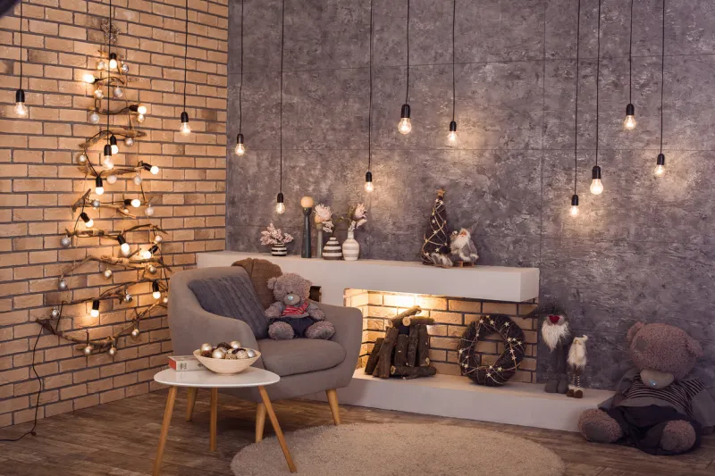 creative wooden christmas tree at the brick wall of loft style room with burning bulbs garland and modern fireplace scandinavian winter interior of room horizontal
