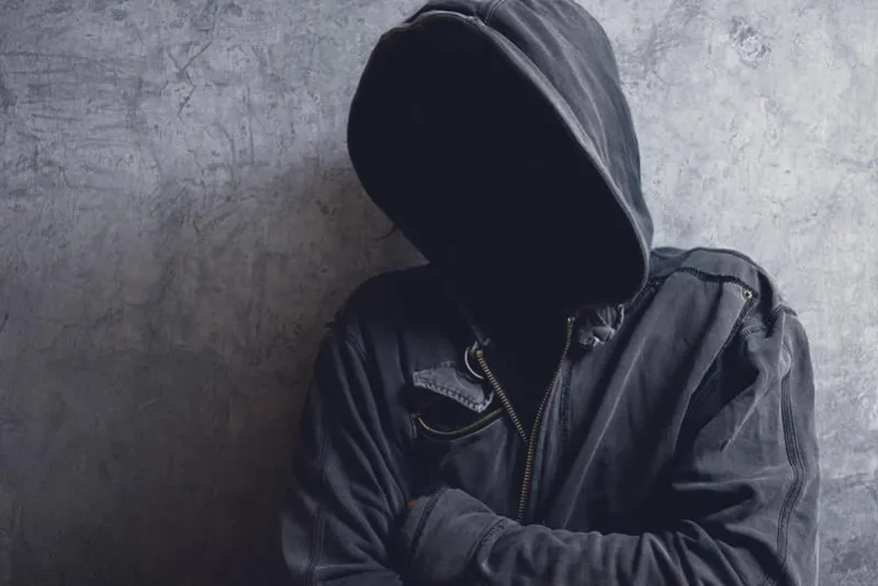 faceless unknown and unrecognizable man with hood in dark room, spooky criminal person