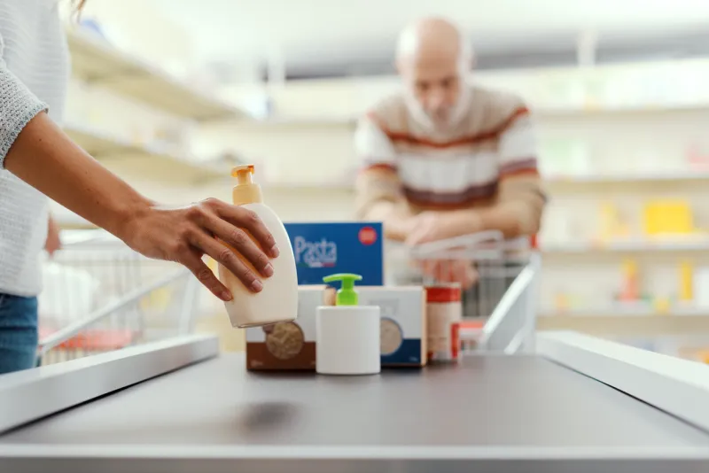 customer placing groceries on the supermarket checkout conveyor belt, hands close up