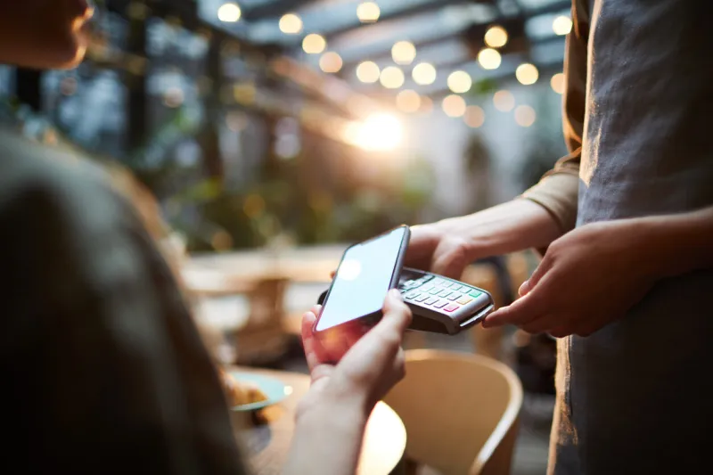 close-up of unrecognizable woman using modern gadget while making online payment in cafe, nfc technology concept