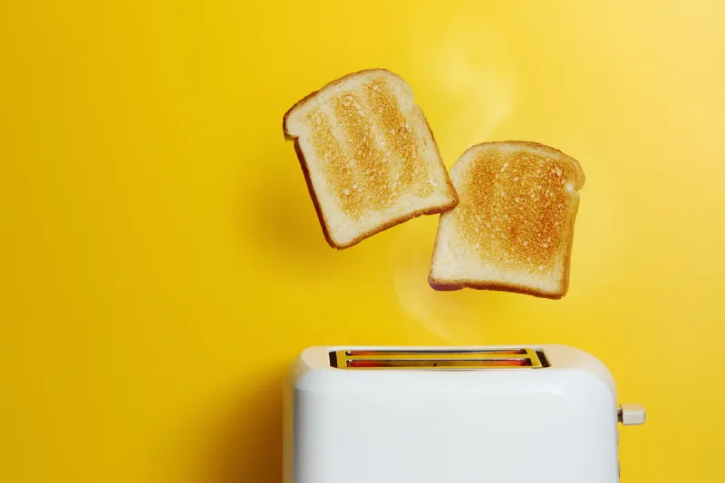 slices of toast jumping out of the toaster against yellow background