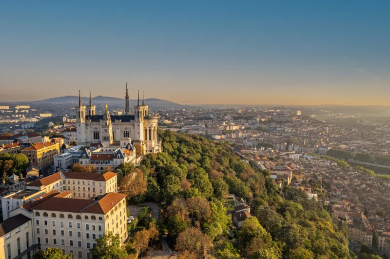 the drone aerial view of the basilica of notre-dame de fourvière and metallic tower at sunrise in lyon, france