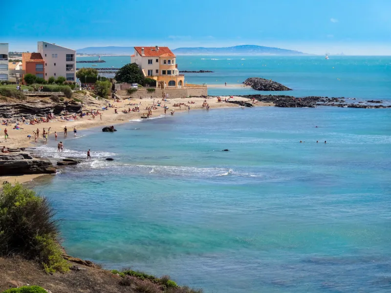bird's eye view of the tip of cap d'agde mixture of rocks, sunny buildings on a sea background