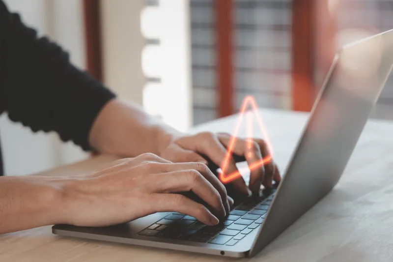 warning hacked alert or it staff , programmer, developer using computer laptop with triangle caution warning sign for notification error and maintenance concept