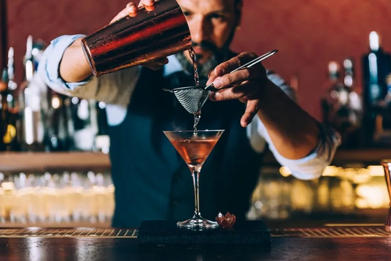 expert barman is making cocktail at night club