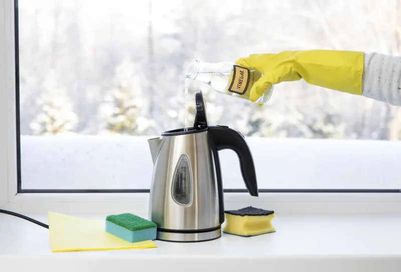 woman pouring natural destilled acid white vinegar in electric kettle to remove boil away the limescale descaling a kettle, remove scale concept