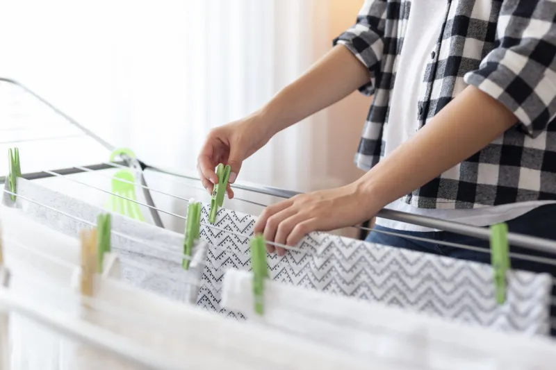 detail of female hands hanging the washing out to dry on a drying rack focus on the clothespin and the hand holding it