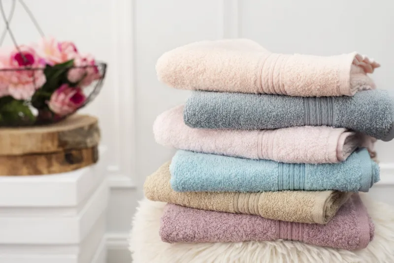 stack of clean soft colorful towels flowers on background