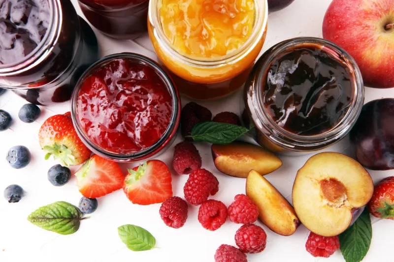 assortment of jams, seasonal berries, plums, mint and fruits