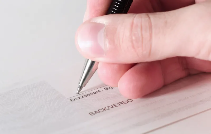 a business person signing the back of a cheque