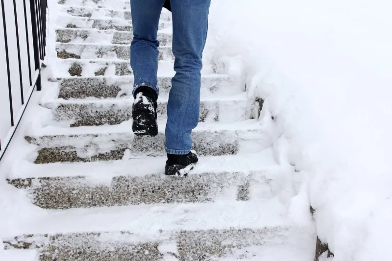 risk of slipping when climbing stairs in winter a man goes up a snow-covered staircase